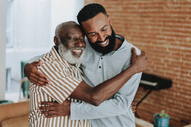 An older man and a younger man embracing warmly, sharing a quiet moment of connection